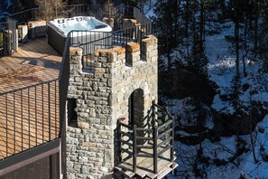 Una torre de piedra con un balcón de madera y un jacuzzi.