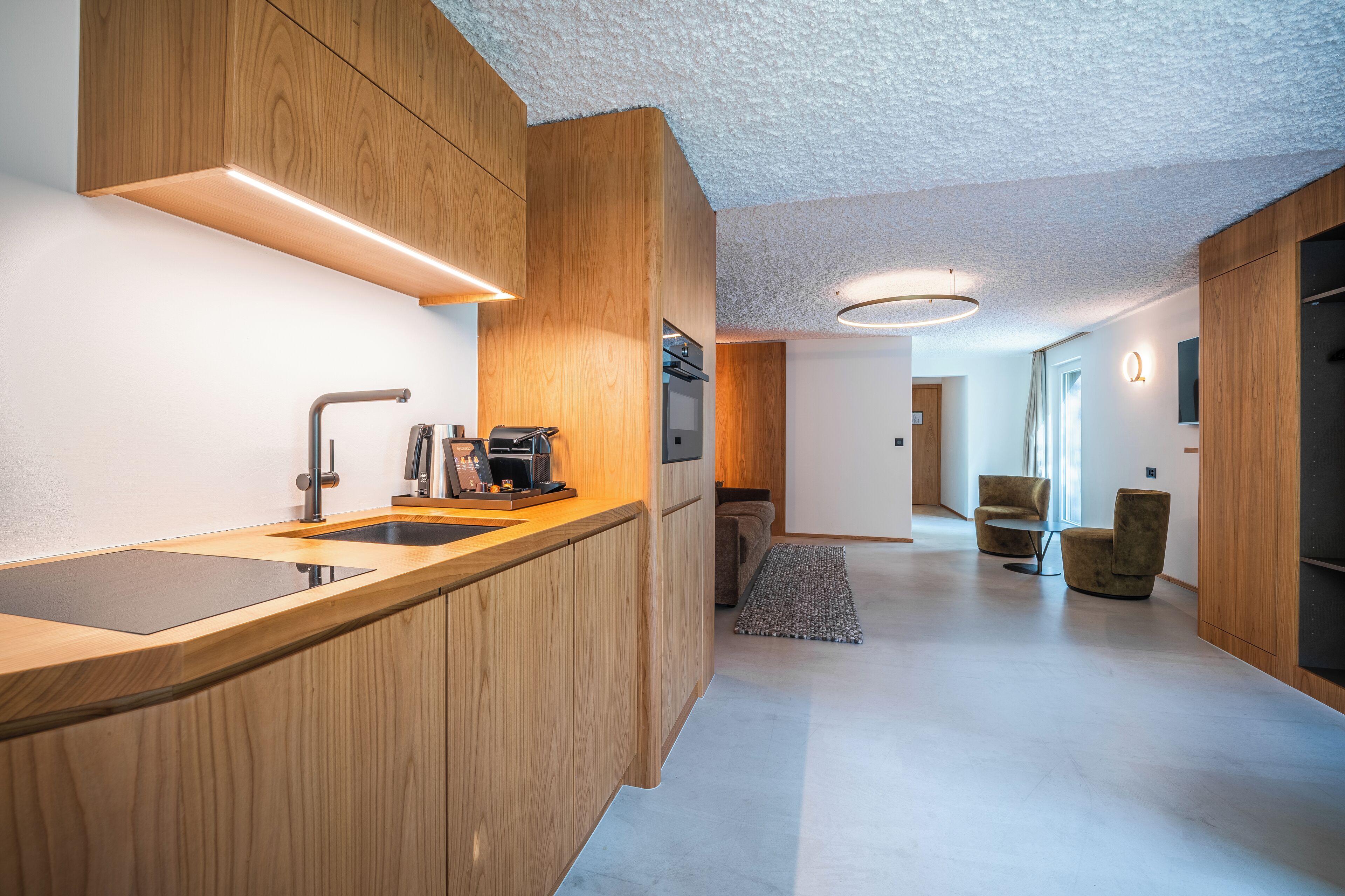 Una cocina moderna con armarios de madera, un lavamanos integrado y una cafetera.