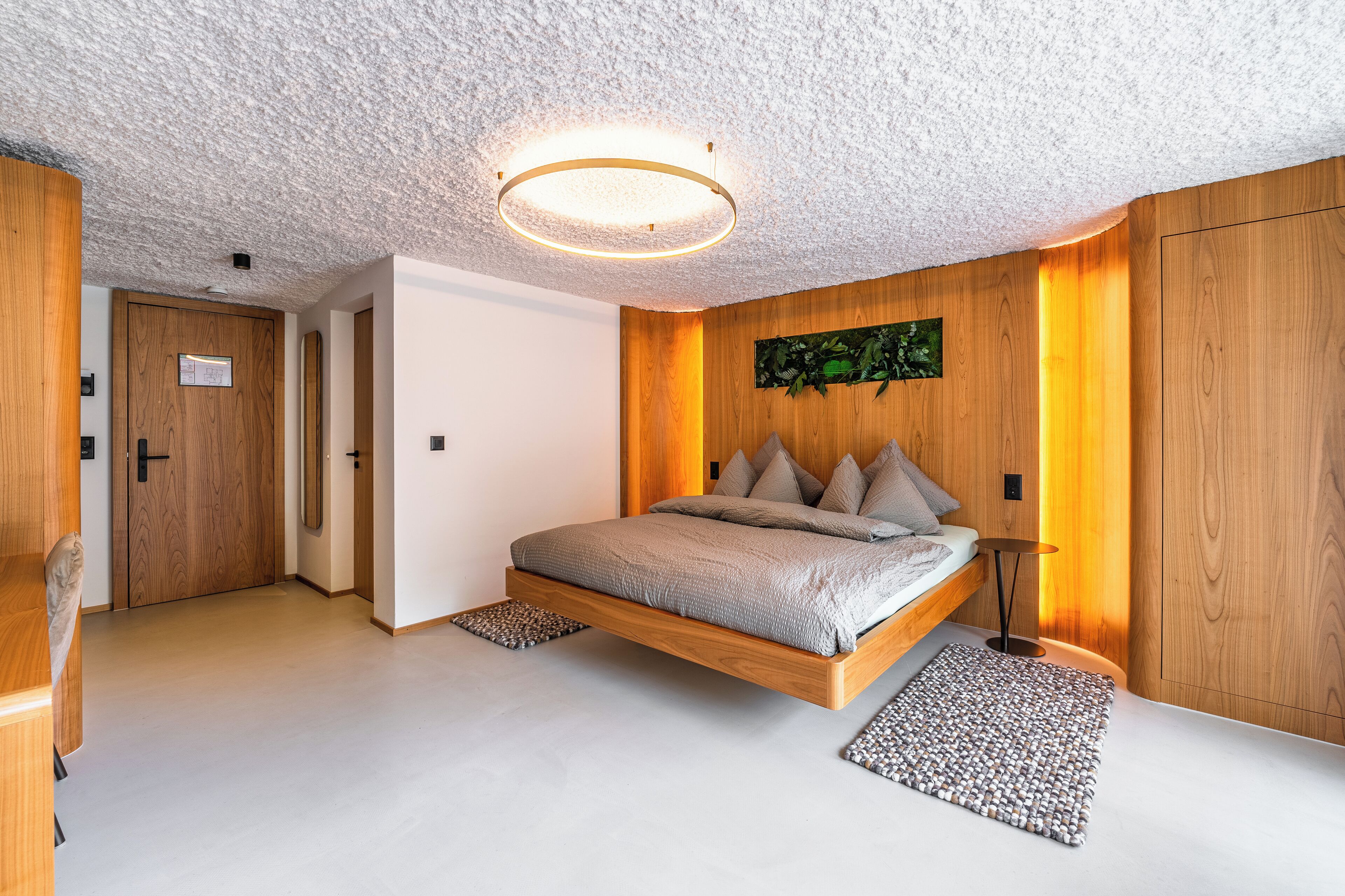 A modern bedroom with a floating bed, wooden walls, and a ceiling light fixture.