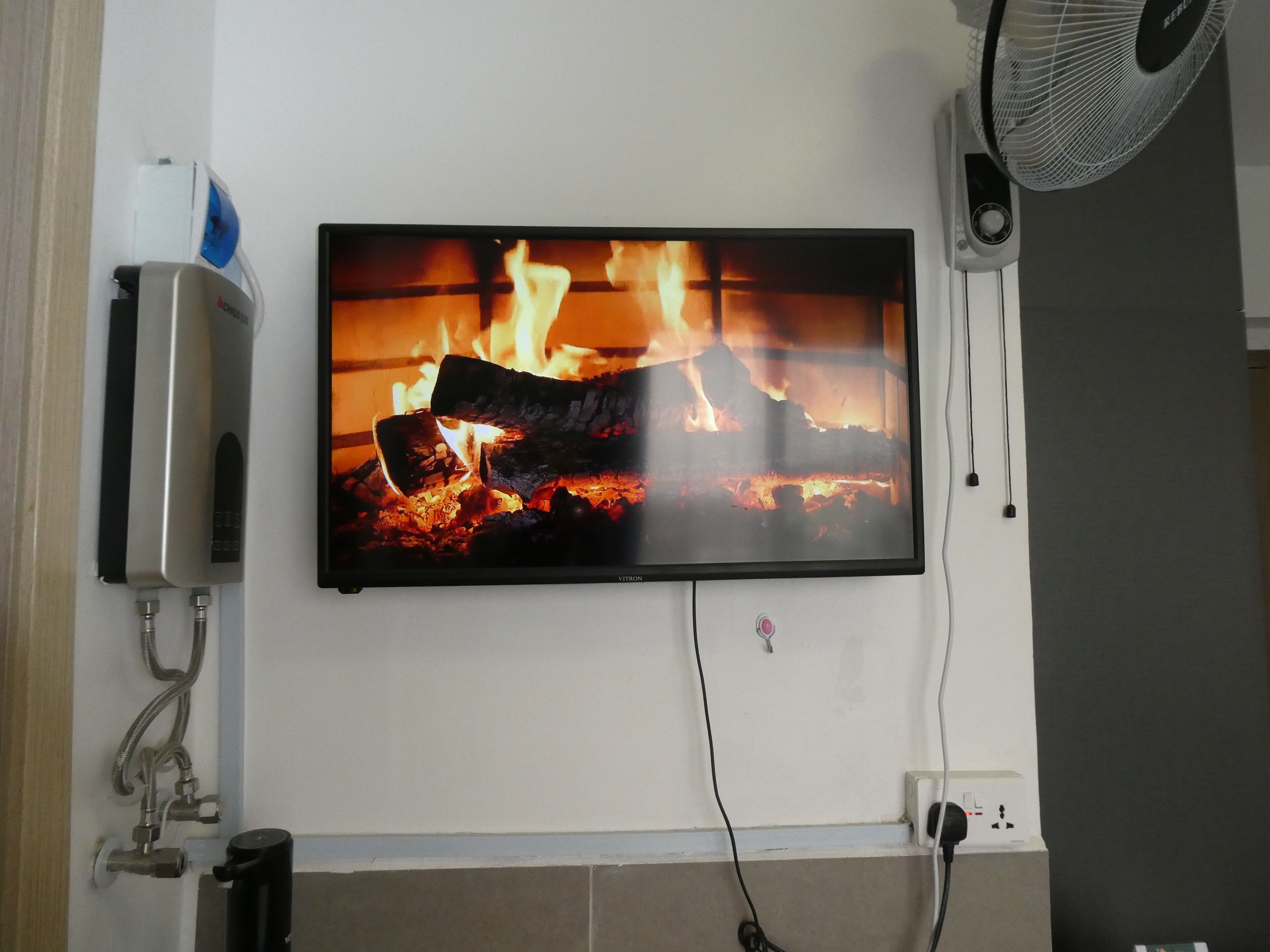 Un téléviseur à écran plat fixé au mur, diffusant une scène d’incendie.