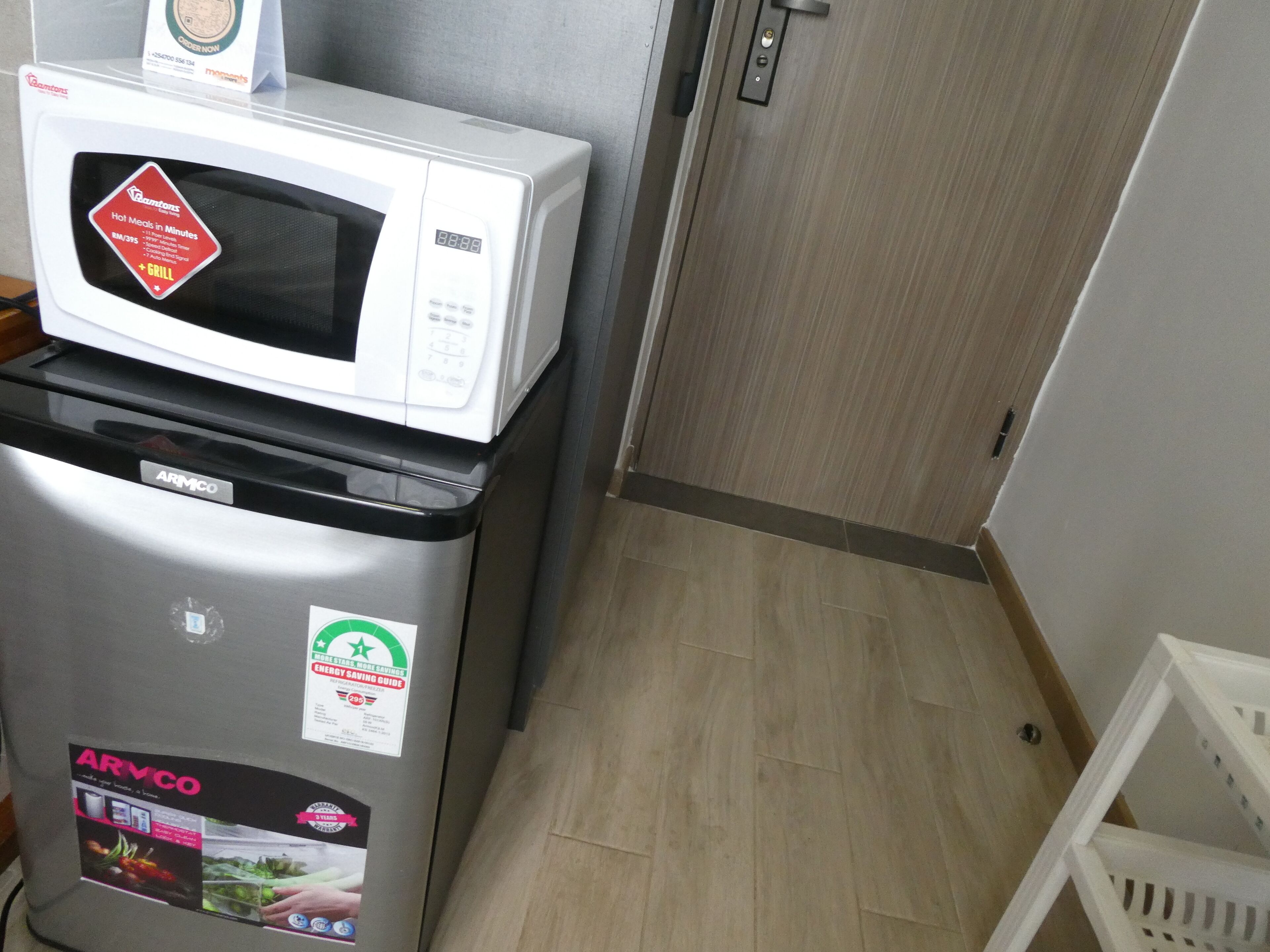 Ein kleiner Küchenbereich mit einer weißen Mikrowelle auf einem silbernen Kühlschrank, beide mit dem Schriftzug 'ARMICO'.