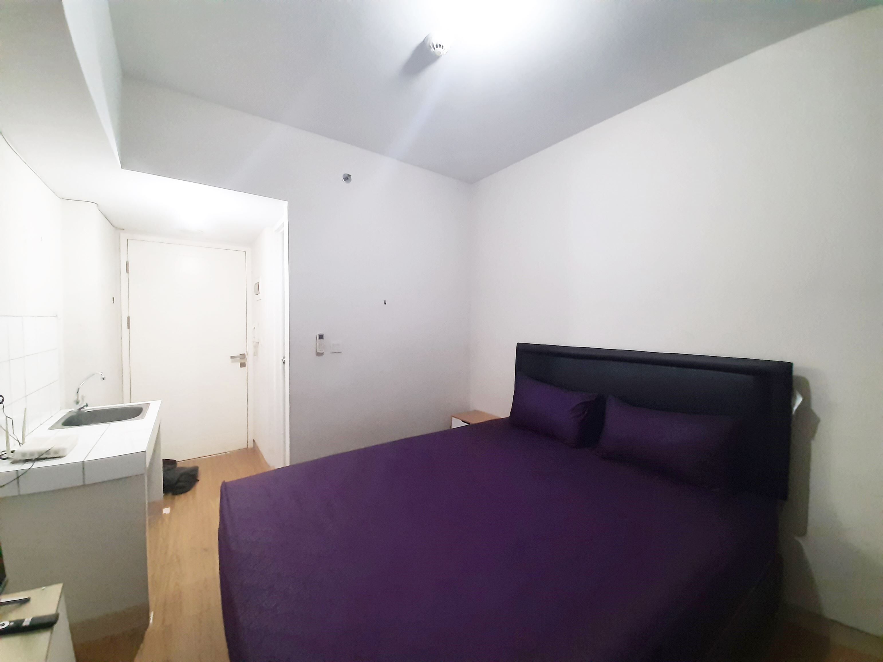 Une chambre avec un lit, un bureau doté d’un lavabo et une porte.