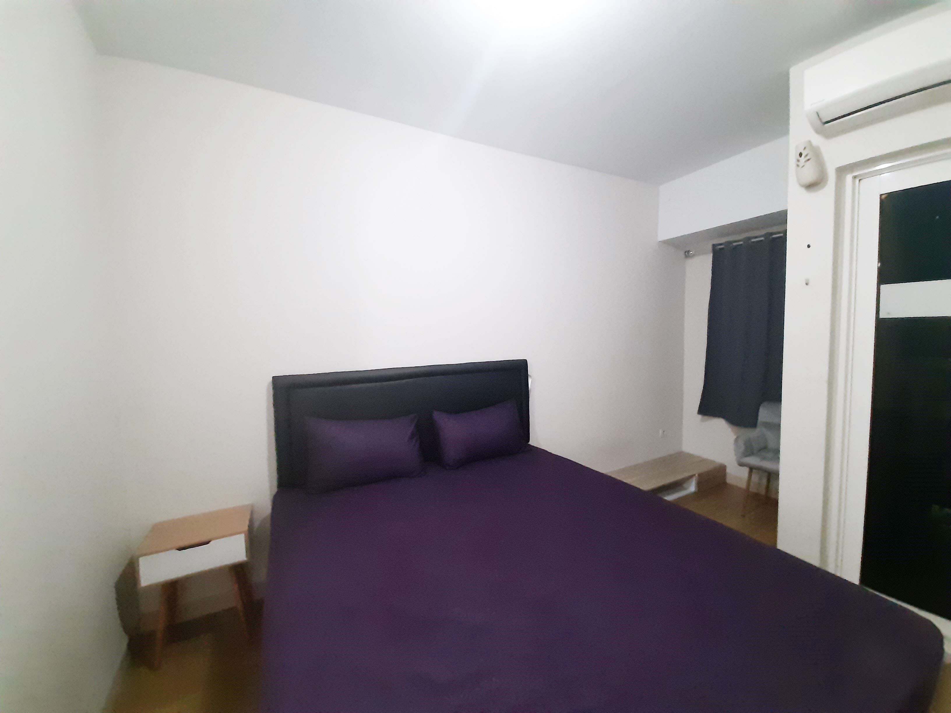 A bedroom with a bed, a nightstand, and a wardrobe.