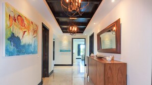 A hallway with a wooden reception desk, a large abstract painting on the left, and a mirror on the right. - Premium Four Bedroom Condo (Punta de Mita)