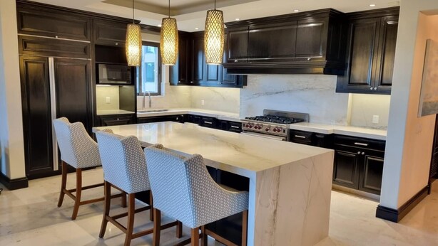 A modern kitchen with dark cabinetry, a large island with bar stools, and pendant lighting. - Premium Four Bedroom Condo (Punta de Mita)