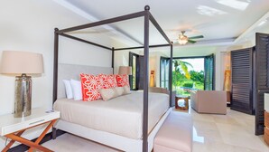 A four-poster bed with a view of a pool and greenery, a bedside table with a lamp, and a small seating area with a table. - Premium Four Bedroom Condo (Punta de Mita)