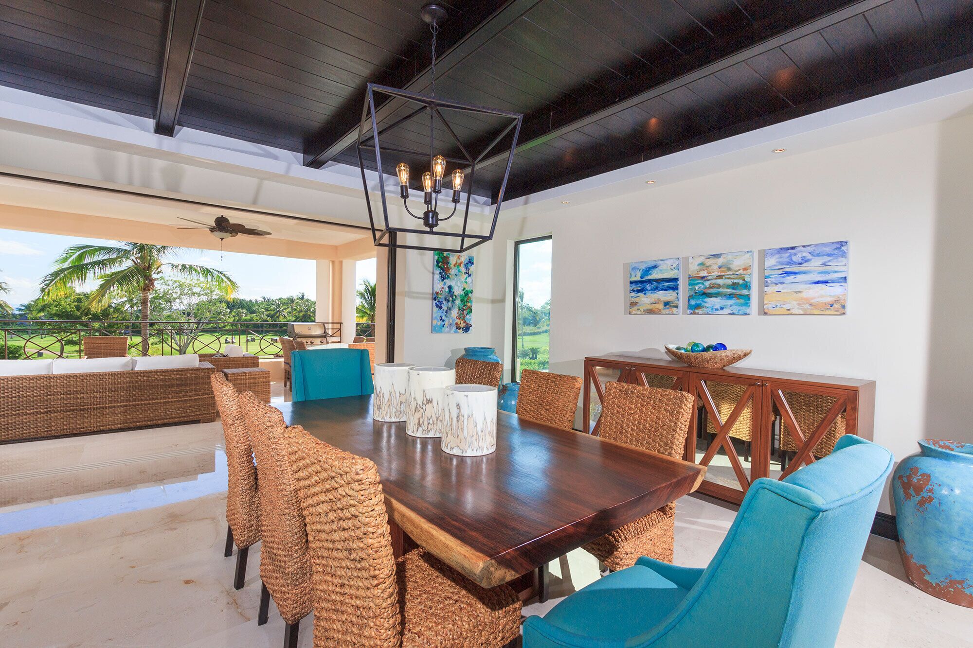 A spacious dining area with a wooden table, wicker chairs, and a view of the outdoors.