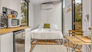 Un dormitorio moderno y funcional con cama, mesitas de noche y ventana.