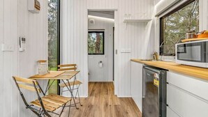 Una cocina compacta con una mesa y sillas de madera, un microondas integrado y un refrigerador pequeño.