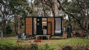 Una casa móvil con zona de cocina, zona de descanso y un pequeño espacio exterior con asientos.