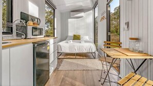 Un dormitorio pequeño con cama, mesitas de noche y ventana.