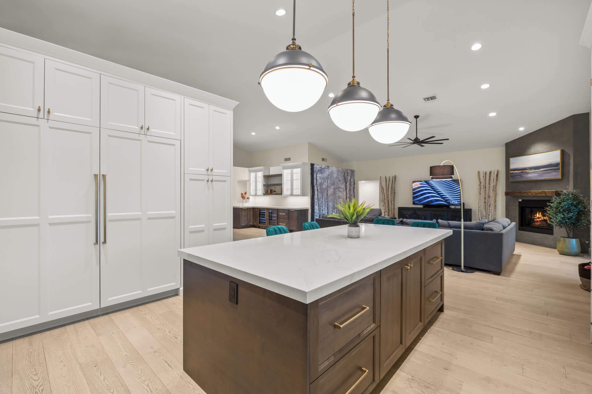 A modern kitchen with white cabinets, a central island, and pendant lighting.