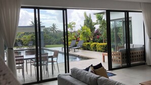 A modern living room with a large sliding glass door leading to an outdoor pool area.