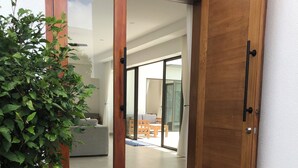 A sliding glass door leading to an indoor space with a tiled floor and a visible outdoor area with a bench and a table.
