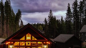 A cabin with a porch, large windows, and a hot tub.