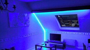 Un salon moderne doté d’un plafond en pente, d’un téléviseur à écran plat, d’une table basse et d’un canapé.