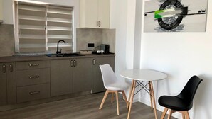 Une cuisine moderne avec un coin repas, comprenant une table blanche et deux chaises, une noire et une blanche.