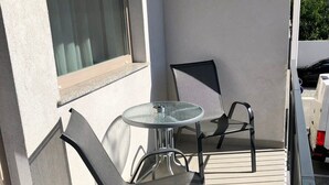 Un balcon avec une petite table ronde et deux chaises.