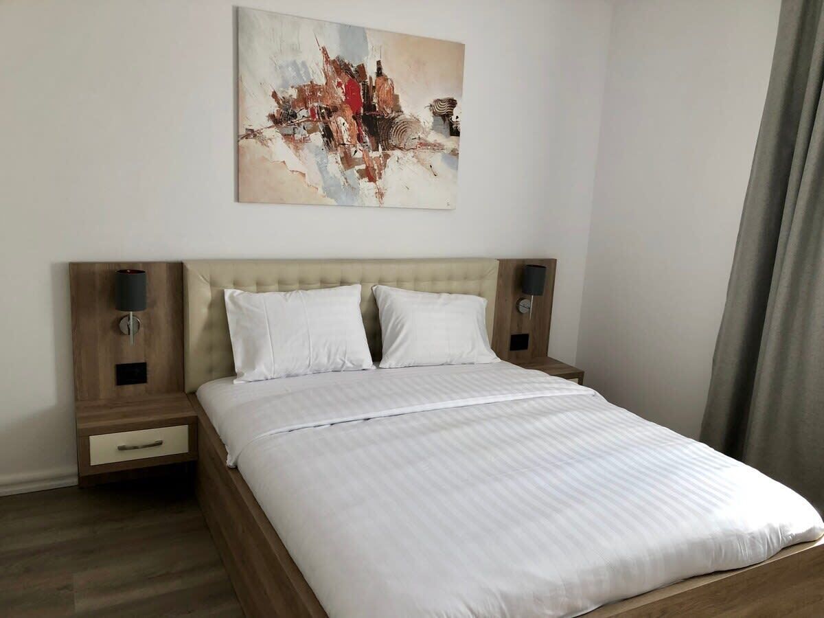 Une chambre d’hôtel avec un lit, une table de chevet, une lampe et un tableau au mur.