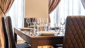Een eettafel gedekt met borden, glazen en bestek, met een comfortabele stoel ervoor.