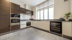 Een moderne keuken met ingebouwde apparatuur, een groot raam en een wijnkoeler.