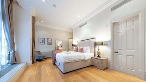 Een moderne slaapkamer met een groot bed, nachtkastjes, een kledingkast en een raam met gordijnen.