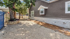 A residential building with a gravel driveway, a tree with an American flag, and a blue gate. - The jewel of Mediterranean (San Antonio)