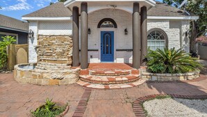 A house with a blue door, stone facade, and a brick pathway leading to the entrance. - The jewel of Mediterranean (San Antonio)