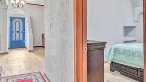 A bedroom with a bed, a dresser, and a door leading to another room. - The jewel of Mediterranean (San Antonio)