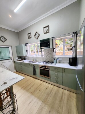 A modern kitchen with a built-in microwave, oven, and gas stove. There are cabinets, a sink, and a window with curtains.