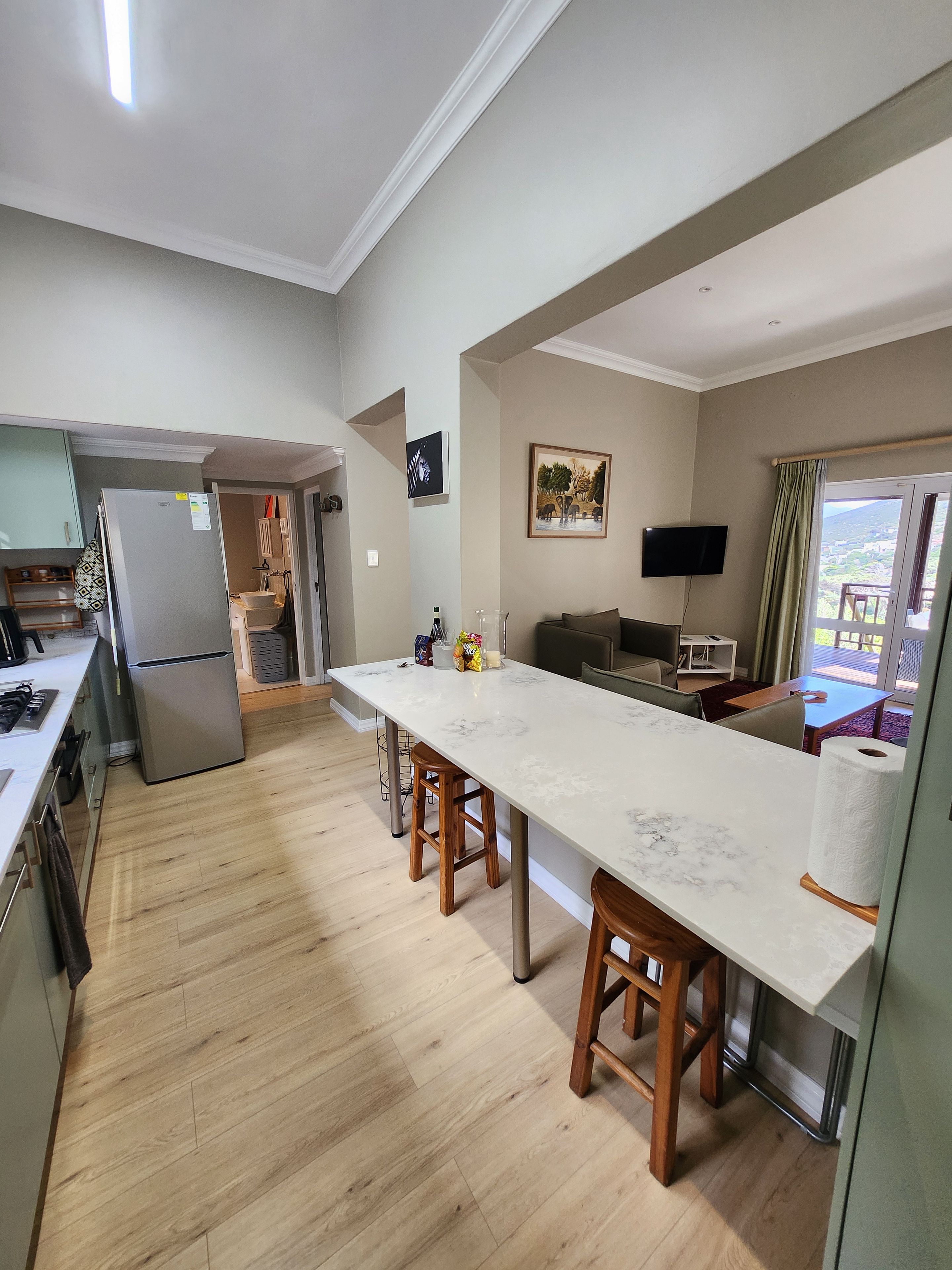 Eine moderne Küche mit Marmorarbeitsplatte, Holzstühlen und einem eingebauten Kühlschrank.