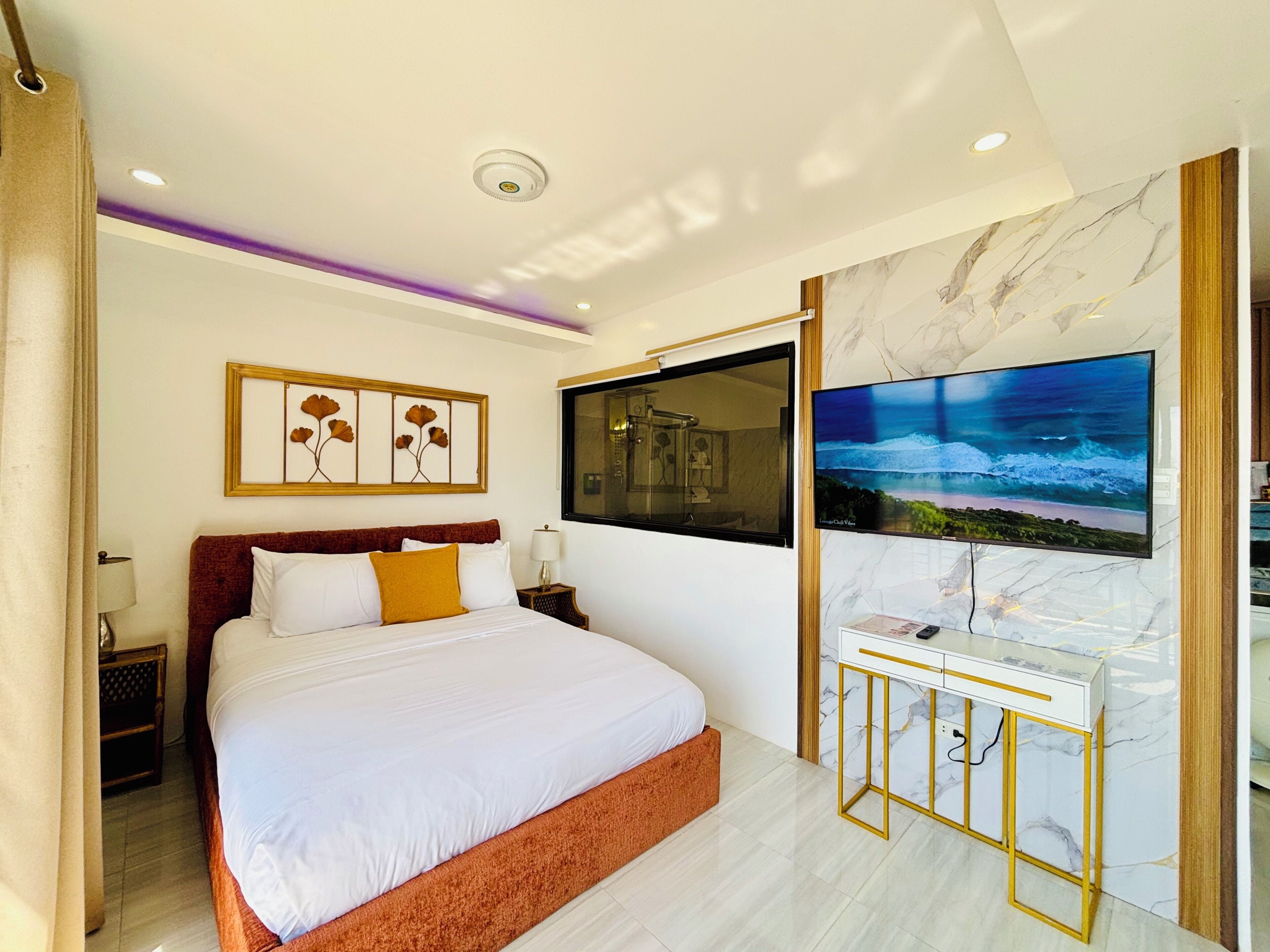 A modern hotel room with a large bed, a TV mounted on the wall, and a marble accent wall.