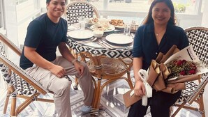 Una pareja sentada a una mesa con vista a la playa y al océano.