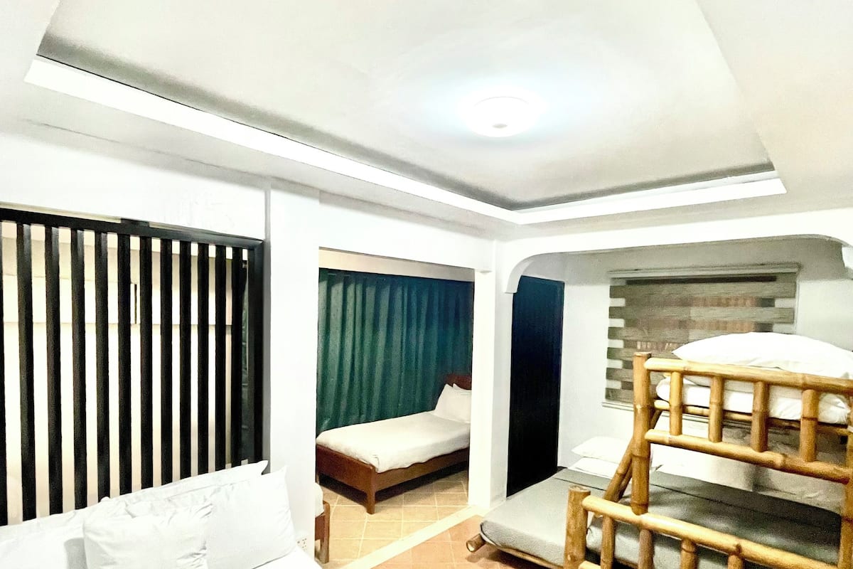 A hotel room with a large bed, a smaller bed, and a bunk bed.