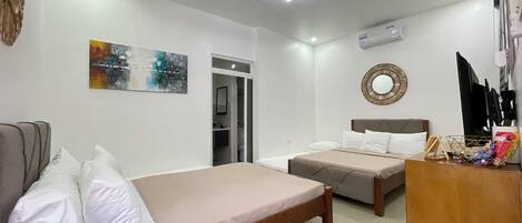 A modern bedroom with two beds, a sofa, a mirror, and a painting on the wall.