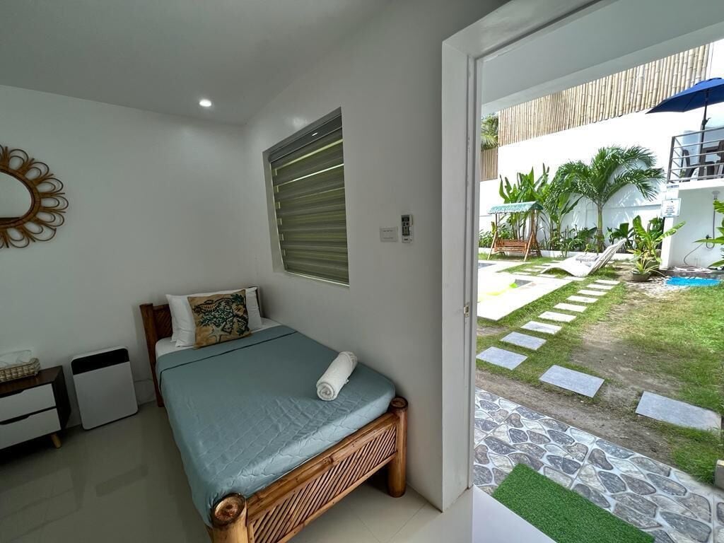 A bedroom with a bed, bedside table, and a window.