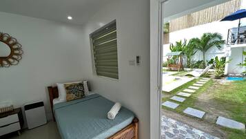 A bedroom with a bed, bedside table, and a window.