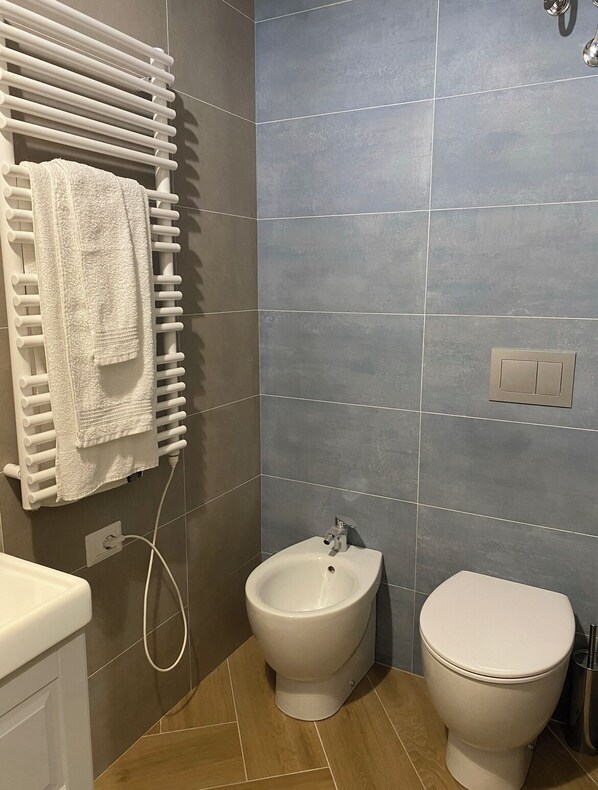 A bathroom with a bidet, toilet, and towel rack.