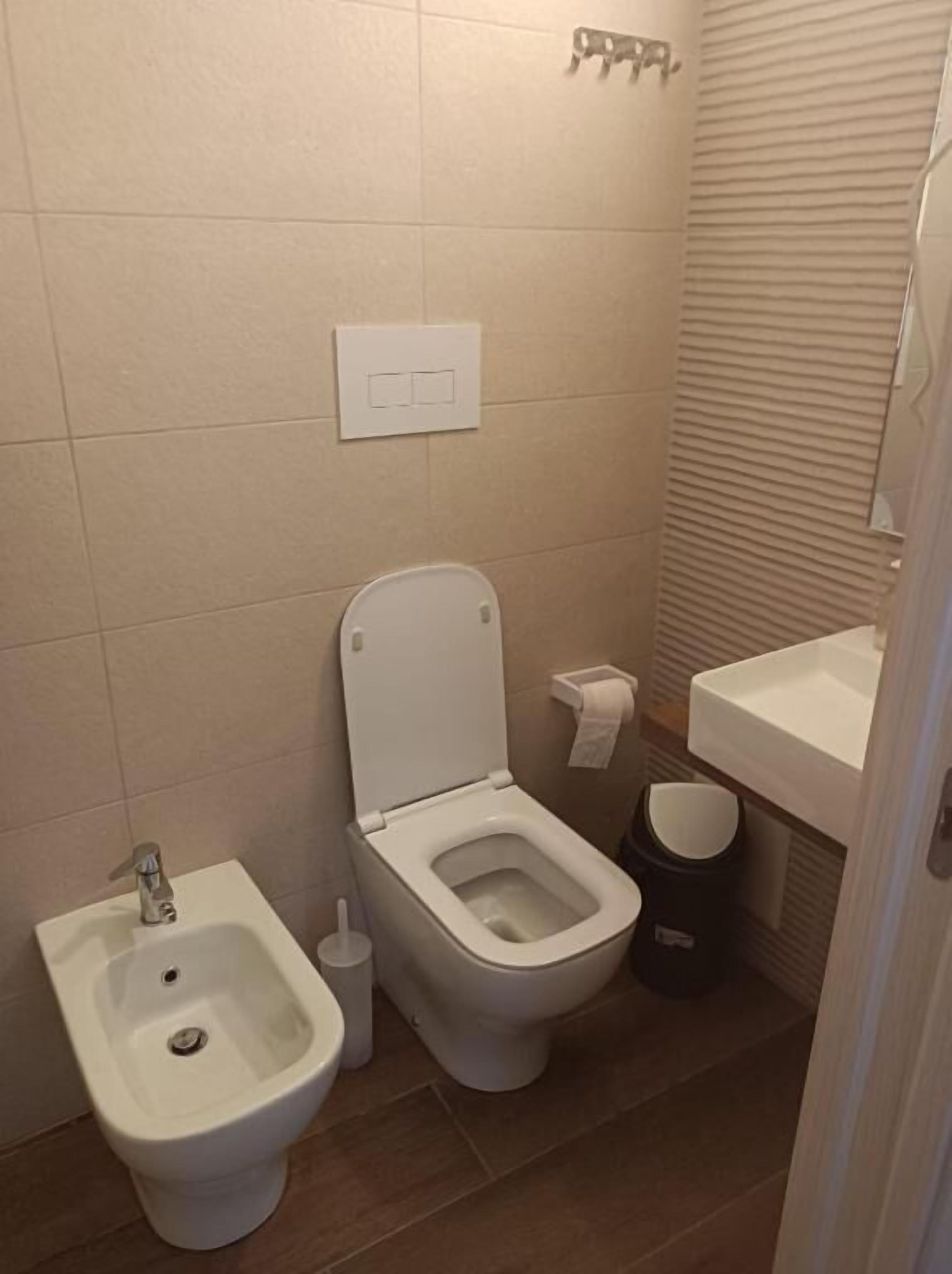 Un baño pequeño con bidé, inodoro y lavamanos.