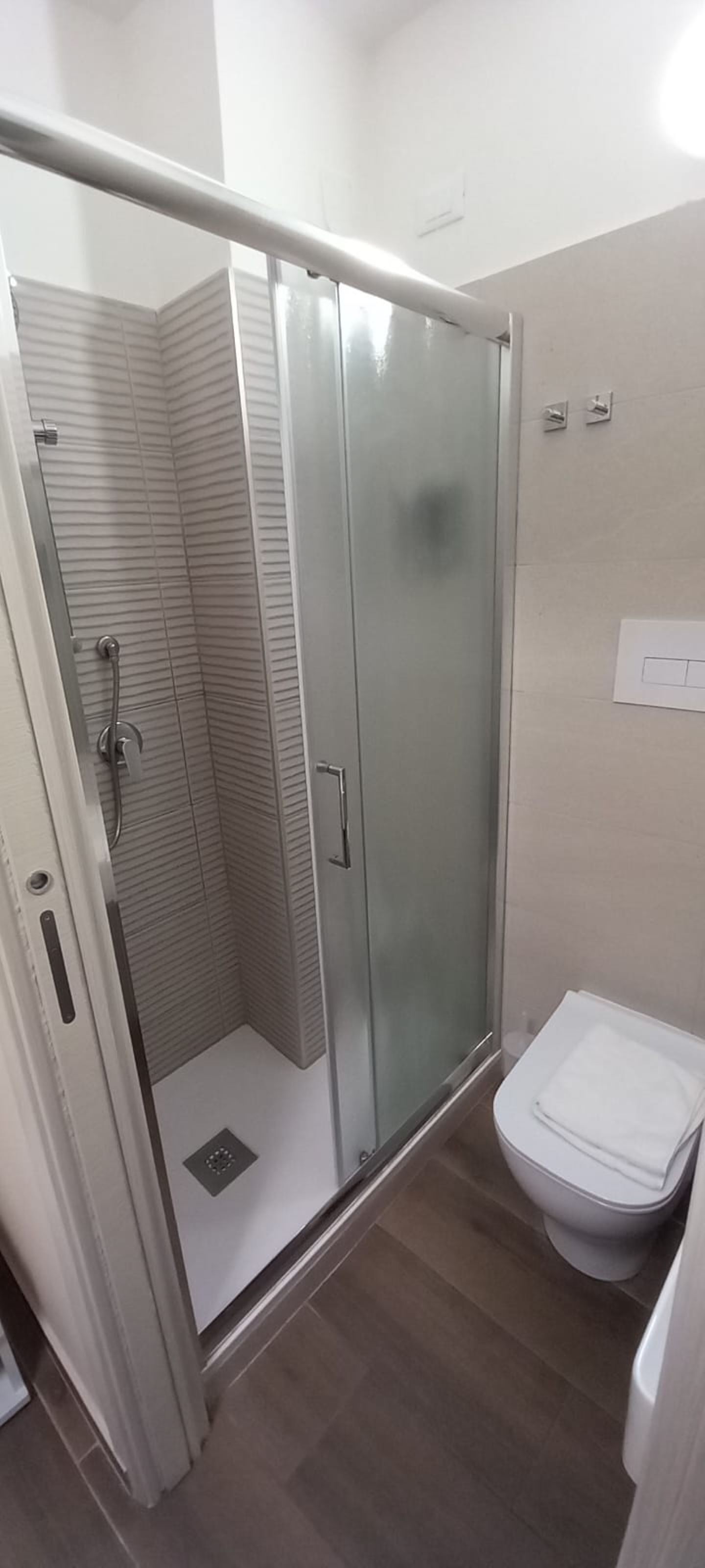 A bathroom with a glass-enclosed shower, a toilet, and a sink.