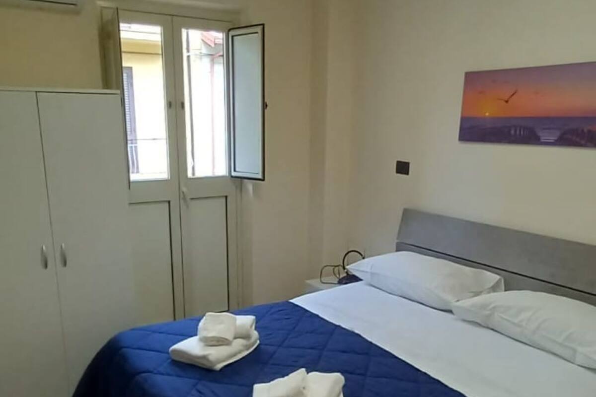 A bedroom with a bed, a painting, and a skylight.