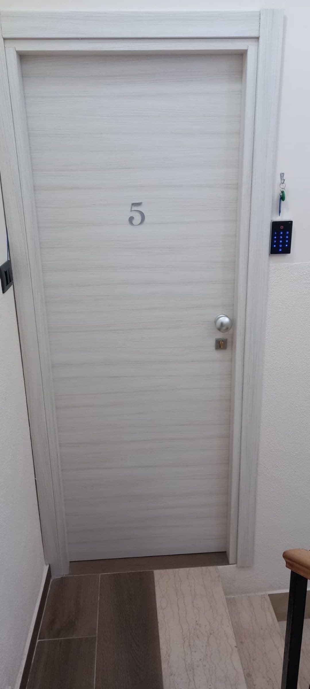 A white door with a keypad lock and a number '5' on it.