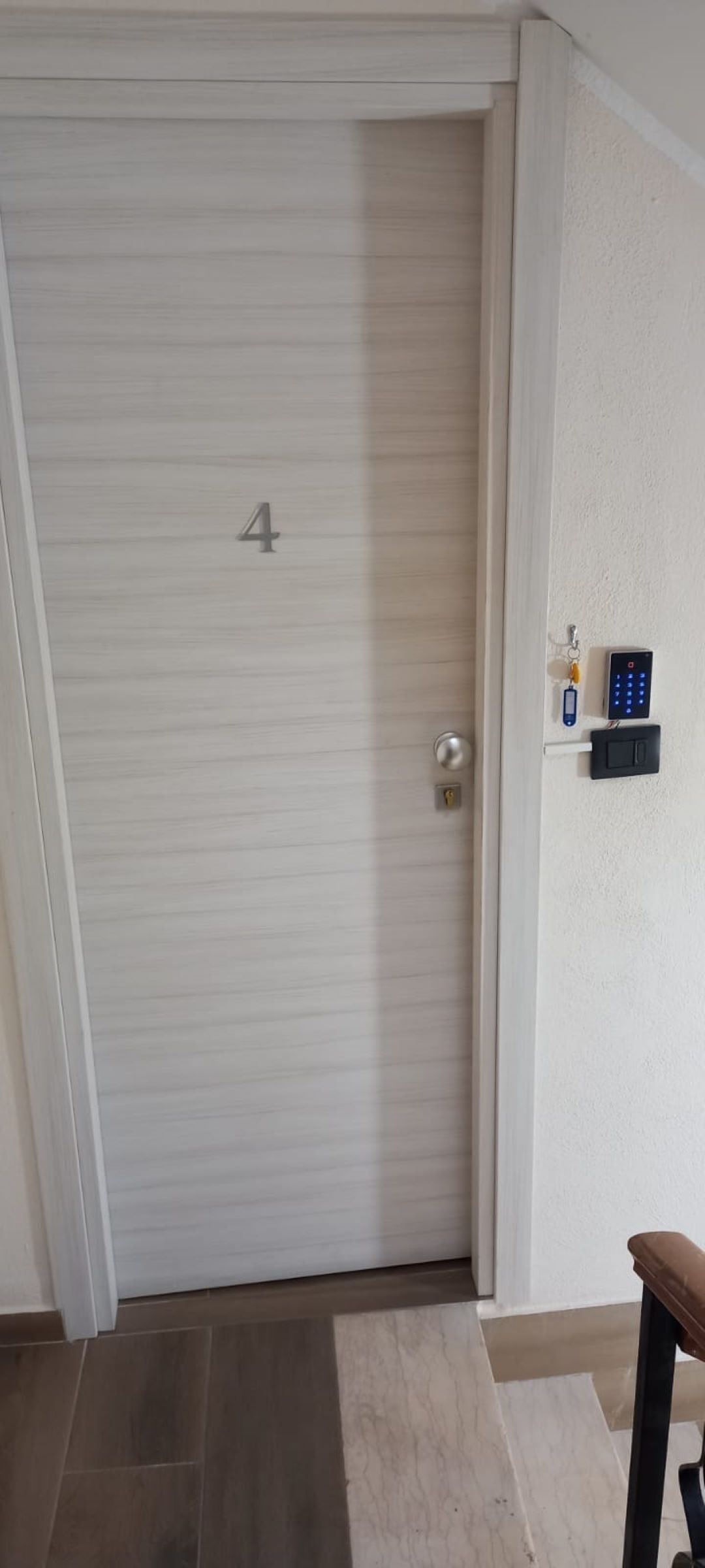Une porte fermée, portant le numéro « 4 », dotée d’un clavier de code et d’un système d’interphone fixé au mur.