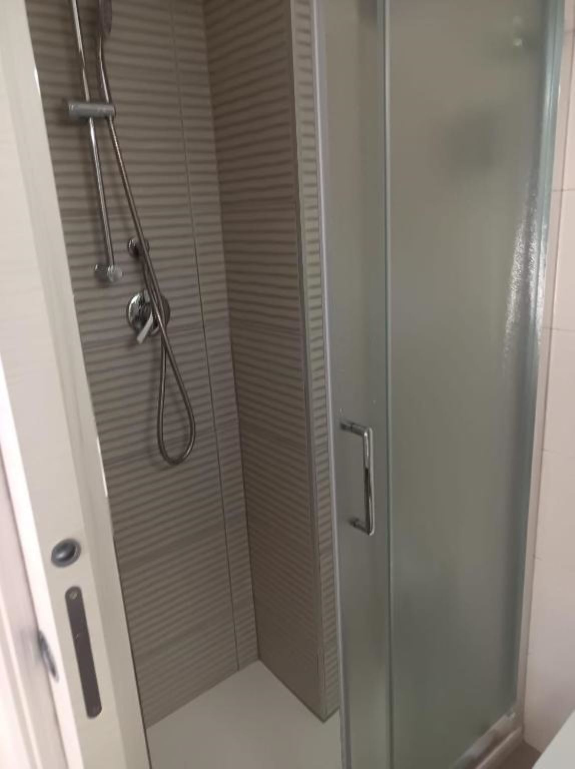 Ducha con puerta de vidrio y cabezal.