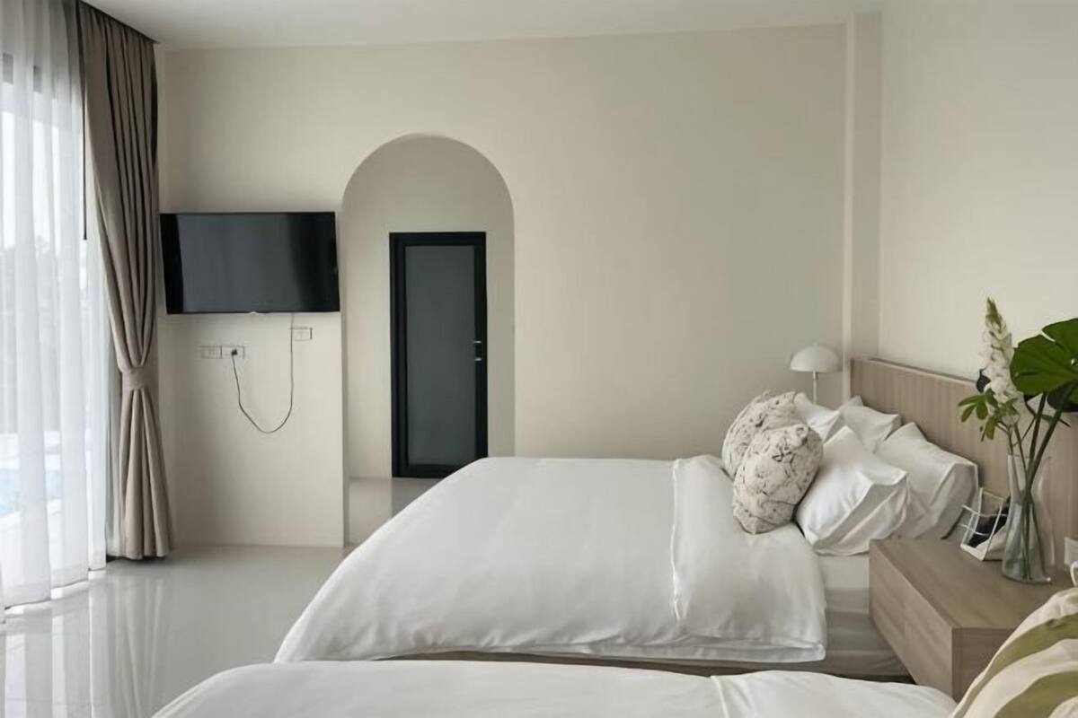 Ein Hotelzimmer mit Bett, Fernseher, Tür und Pflanze.