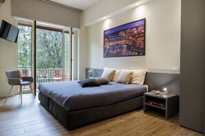 A bedroom with a large bed, a TV mounted on the wall, and a balcony with chairs. - Betty Florence Charming Modern Apartment (Florence)