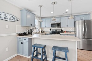 Une cuisine moderne avec des meubles de couleur bleu clair, des appareils en acier inoxydable et un îlot central doté de tabourets.