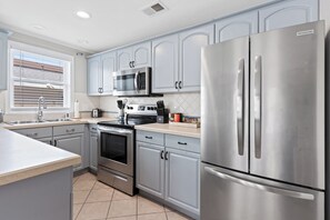 A modern kitchen with stainless steel appliances, grey cabinetry, and a tiled backsplash.