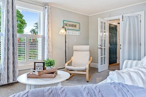 Ein gemütliches Zimmer mit einem Sessel, einem kleinen Tisch mit einer Pflanze und einem Schild mit der Aufschrift 'SEASIDE'.
