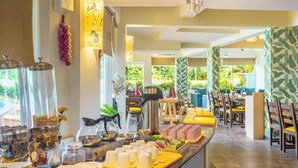 Un'area buffet con diversi cibi, posate, una postazione caffè e un'area salotto con tavoli e sedie.